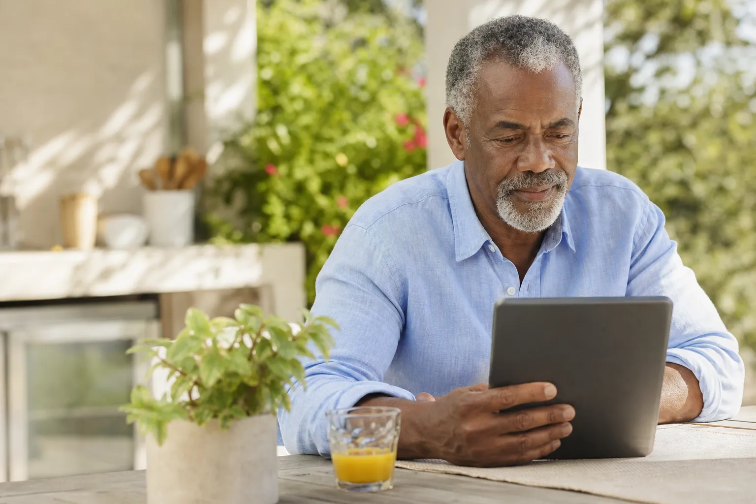 Retired man reviewing retirement income strategy on tablet at outdoor kitchen table